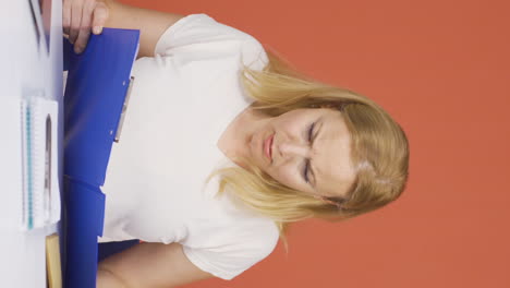 Vertical-video-of-Woman-working-on-laptop-throws-files-angrily.